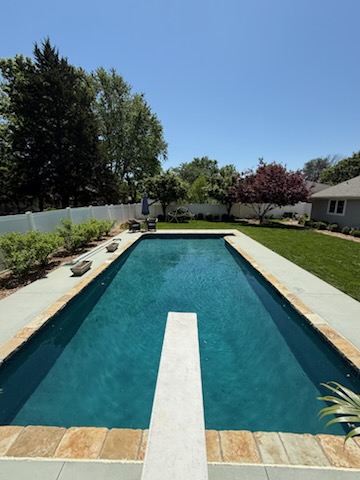 Long lap-style pool with diving board, flagstone coping and manicured lawn