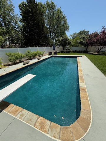 Deep blue plaster pool with flagstone coping, diving board and landscaped border