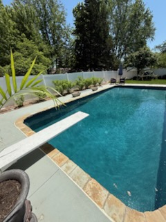 Backyard pool with diving board, planter beds and privacy fencing