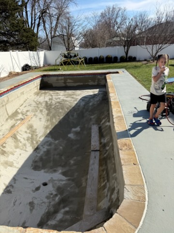 Drained pool mid-renovation with fresh substrate before new plaster